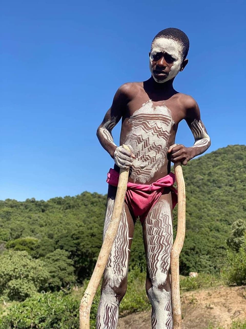 Omo Valley indigenous youth on walking stilts with traditional body paint